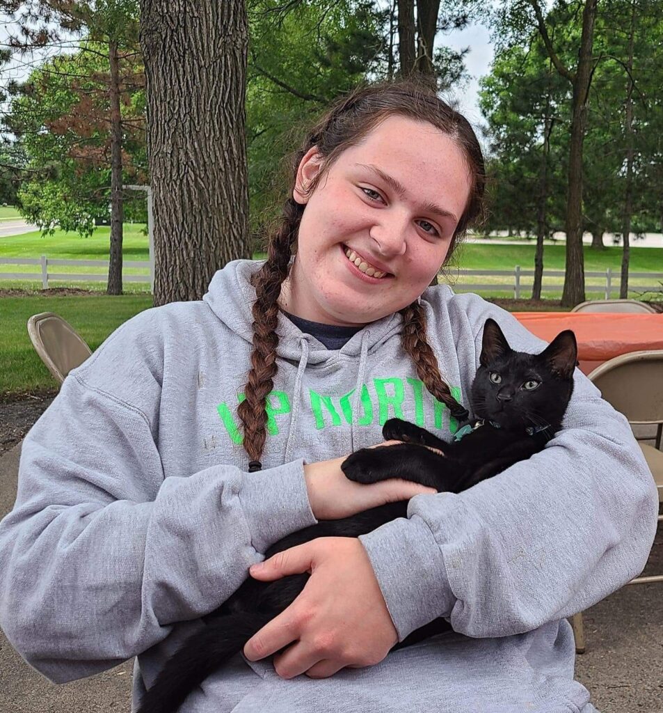 a woman smiling with a black cat in her arms