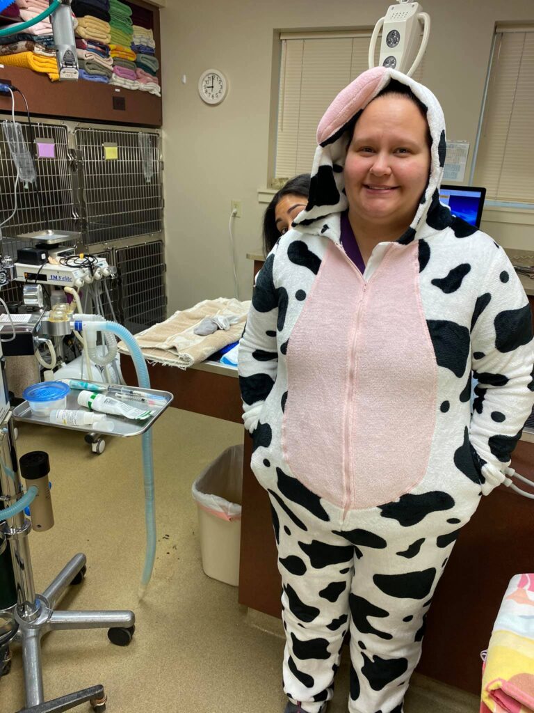 Woman smiling wearing onesie pajamas with cow print, standing near surgery equipment