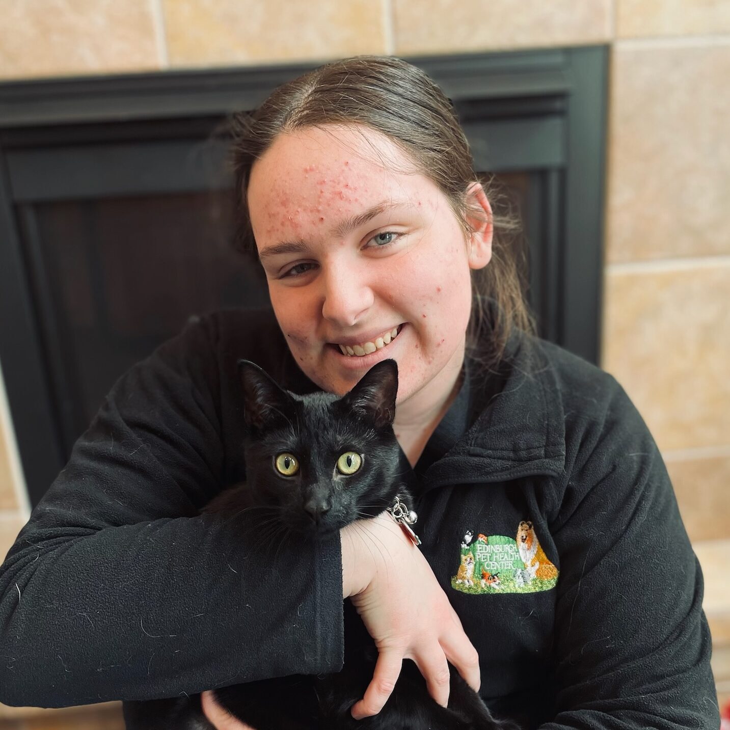 woman smiling holding a black cat in her arms